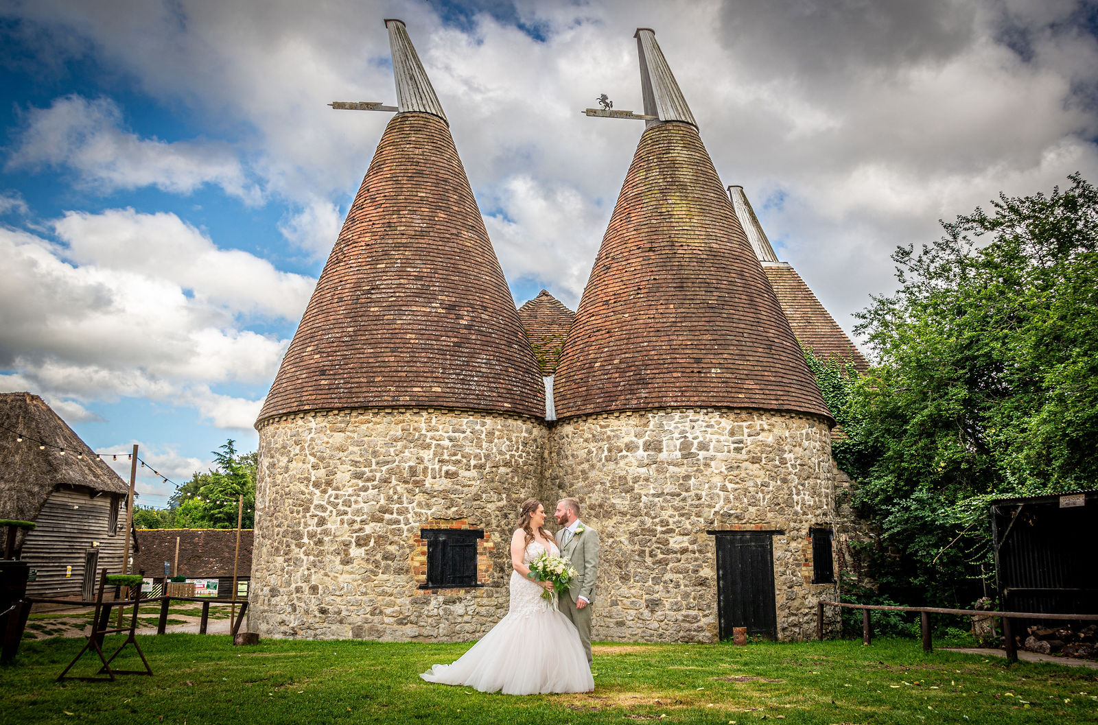 Couples portrait in front of oast houses at Kent Life Wedding Venue in Maidstone