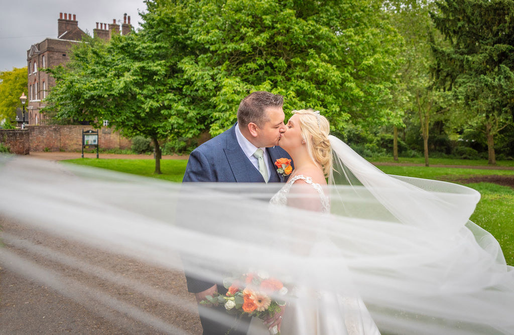 The veil sweeps around a couples portrait at The Vines of Rochester wedding venue in Kent