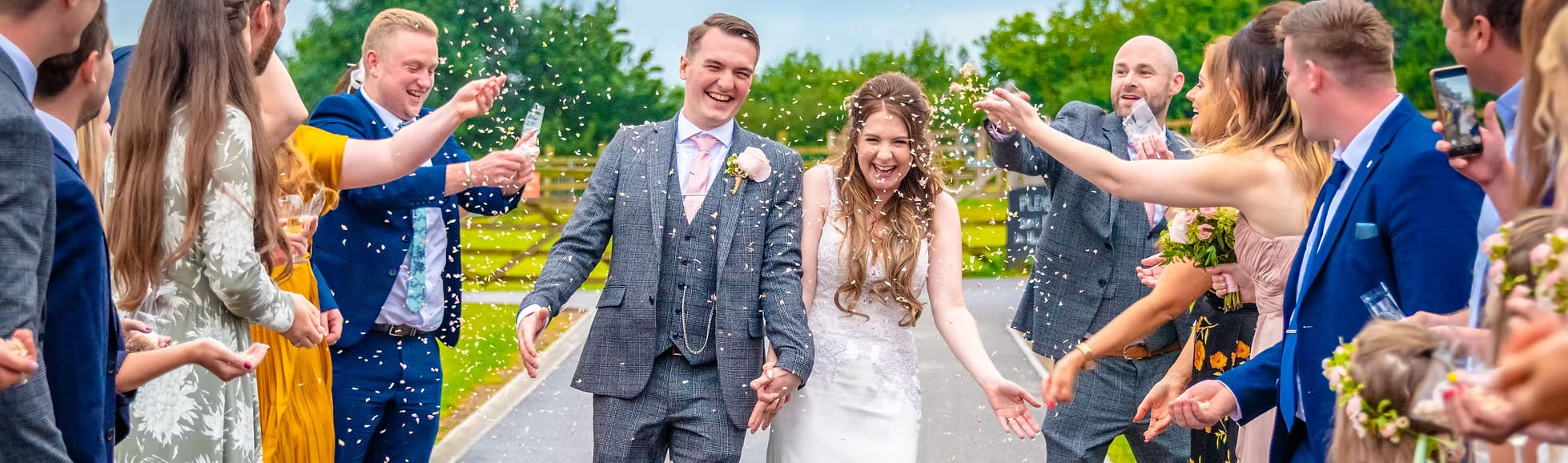 Wedding photographer capturing bride and groom walking through confetti